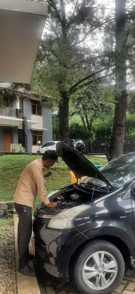 Pengemudi memeriksa mesin kendaraan dinas