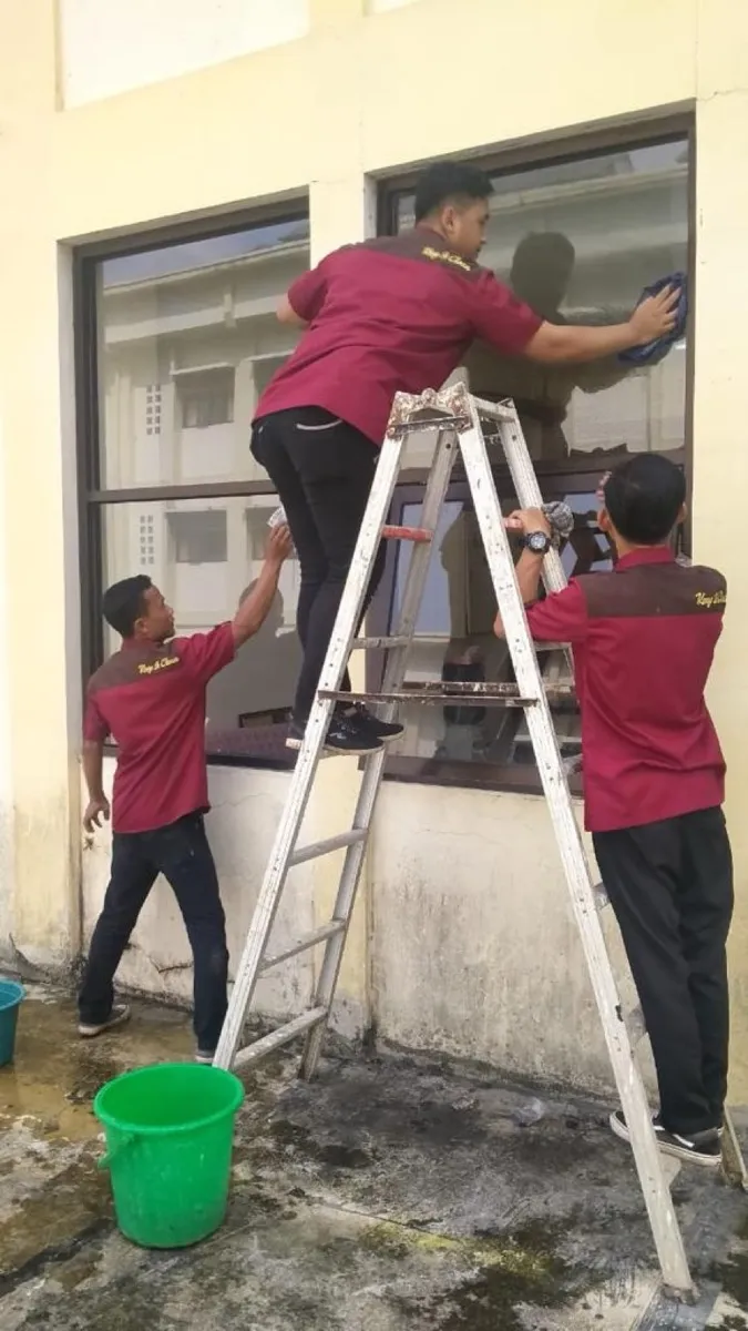 Petugas membersihkan kaca jendela dengan tangga